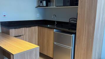 A modern kitchen with wooden cabinetry, a stainless steel refrigerator, and a black countertop.