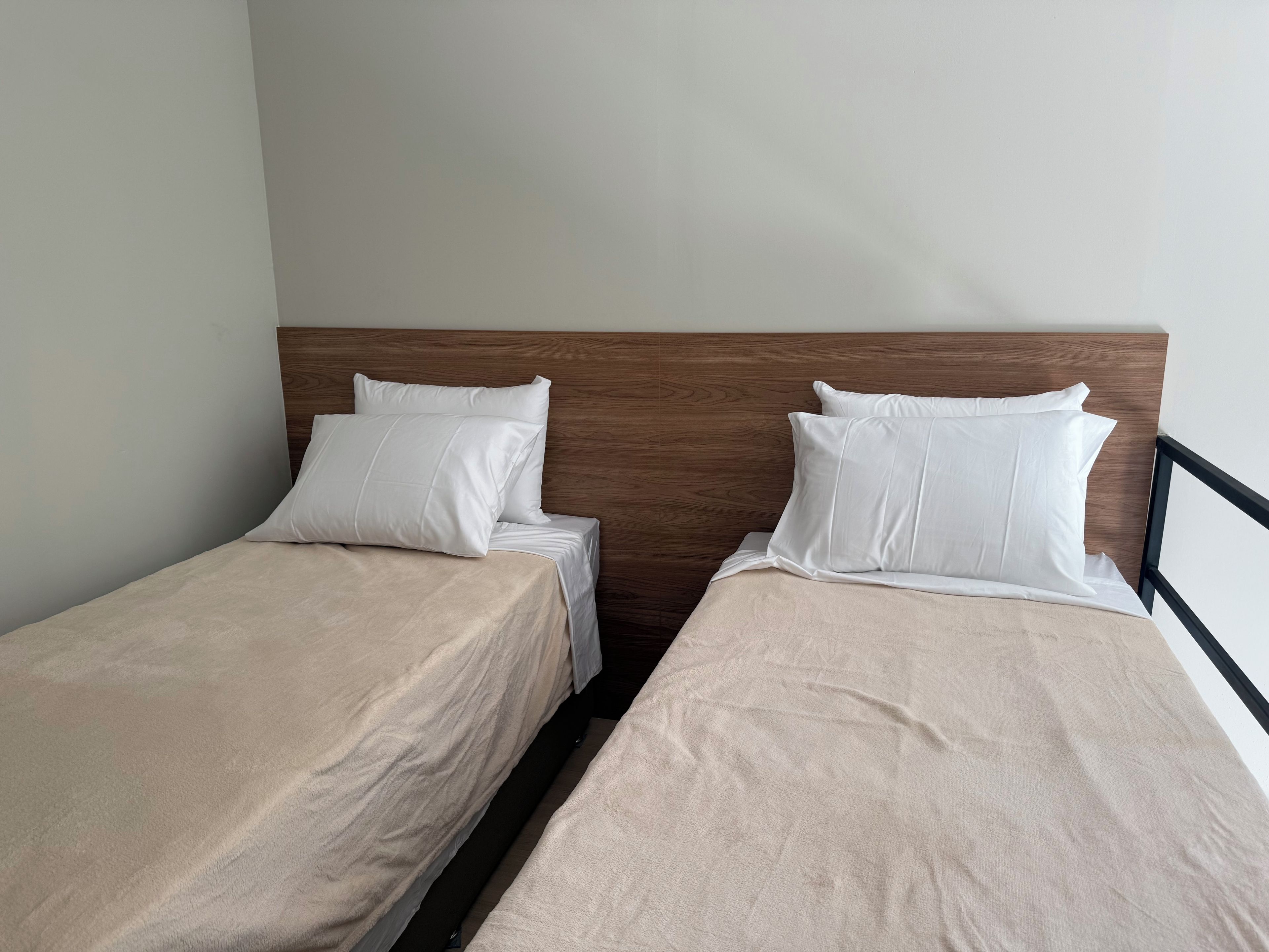 Una habitación con dos camas individuales, cada una con cabecero de madera y ropa de cama blanca.