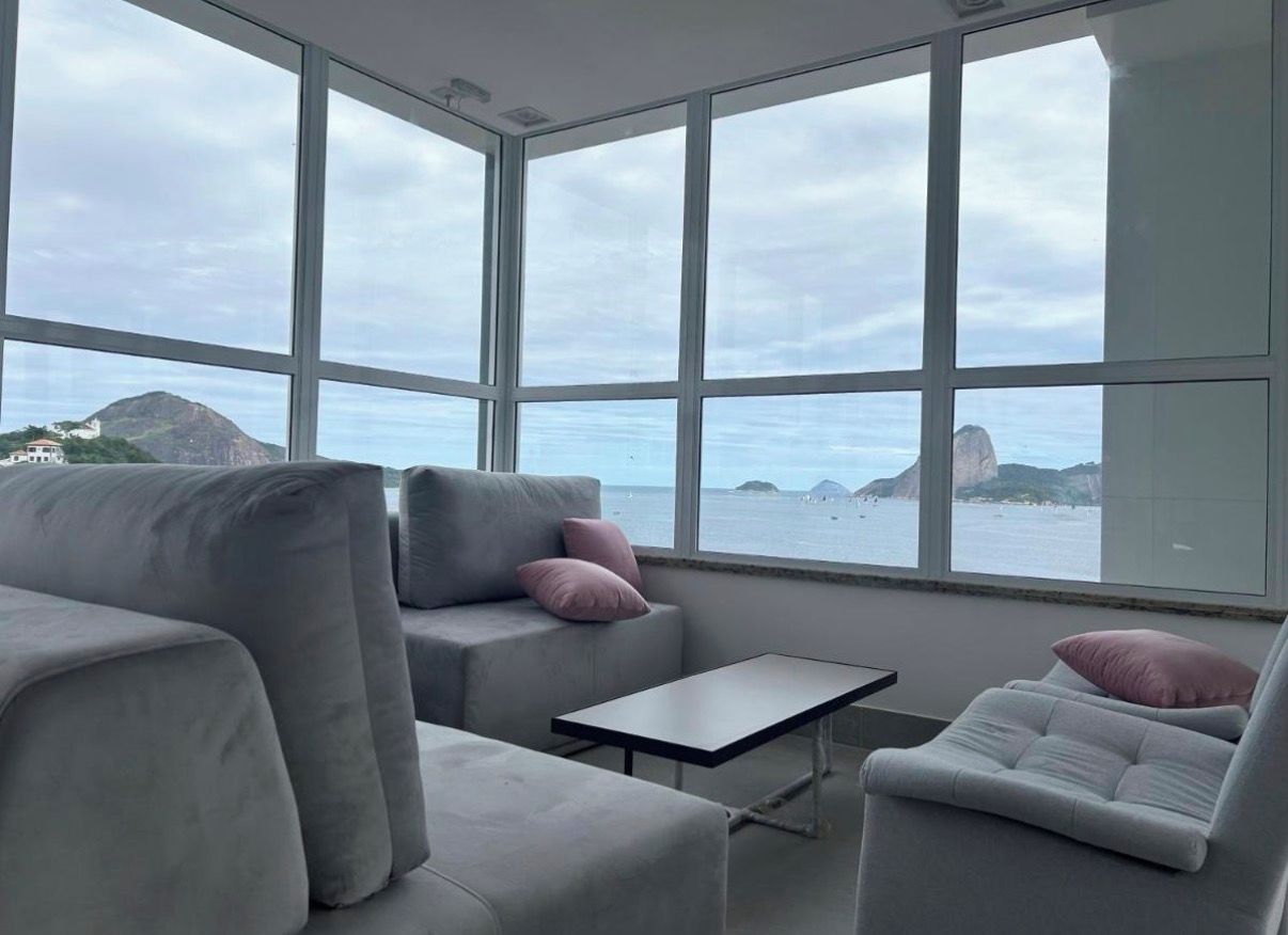Un intérieur moderne doté d’une grande fenêtre offrant une vue sur la mer et les reliefs lointains.