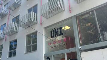 A modern building with a glass entrance labeled 'UNI' and 'SMART LIVING'.