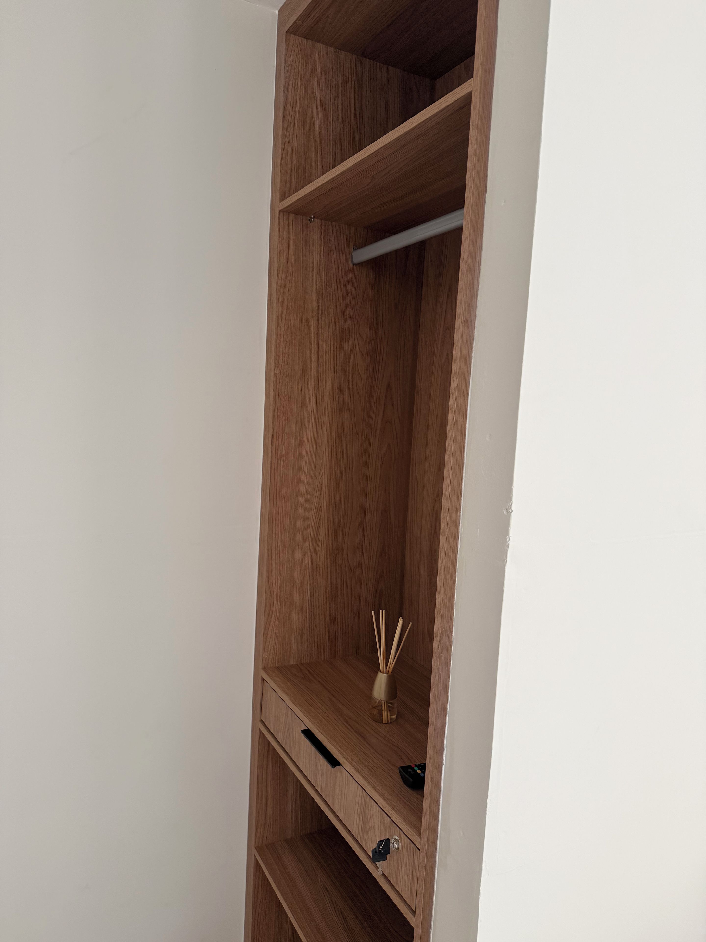 Een houten garderobe met verschillende planken en een kledingroede.