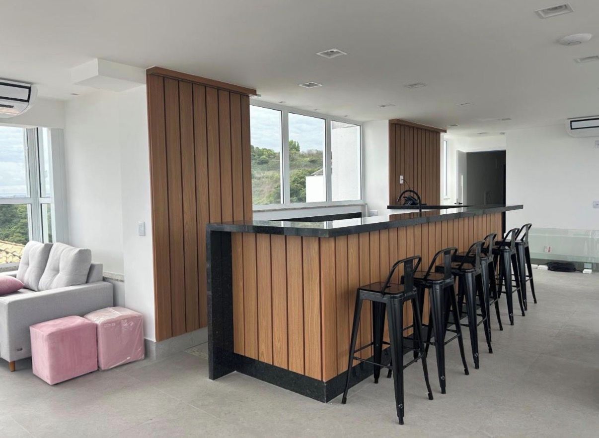 Une cuisine moderne avec un îlot central en bois, des tabourets de bar et une grande fenêtre.