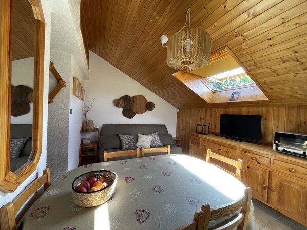 A cozy room with a dining table, a sofa, a TV, and a ceiling fan. - The Ski Apartment (4 People) Valley view, close to the slopes and downtown. (Saint-Gervais-les-Bains)