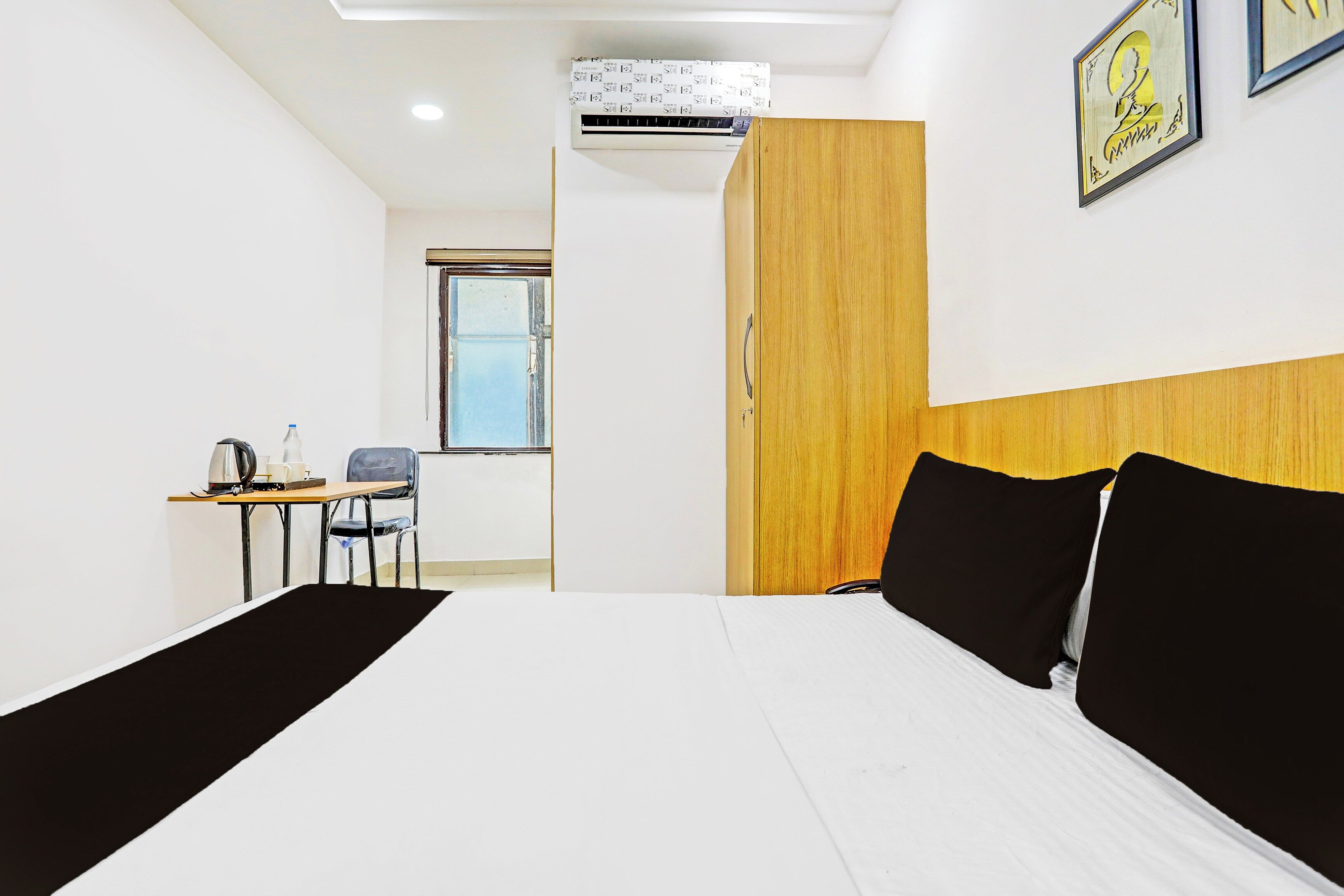 A hotel room with a bed, a desk, a chair, and a window.