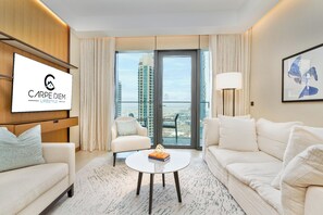 A modern hotel room with a large window, a flat-screen TV, a sofa, a chair, and a coffee table. - Bright apartment in brilliant Dubai with cool AC for your stay (Dubai)