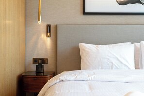 Une chambre d’hôtel équipée d’un lit, d’une table de chevet, d’un téléphone fixé au mur et d’un luminaire.