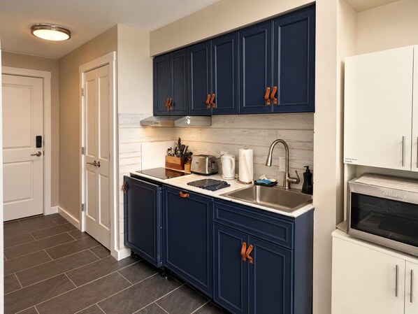 A kitchen with dark blue cabinets, a stainless steel sink, and a built-in oven. - Mountain Retreat in the Village with Hot Tubs (Snowshoe)