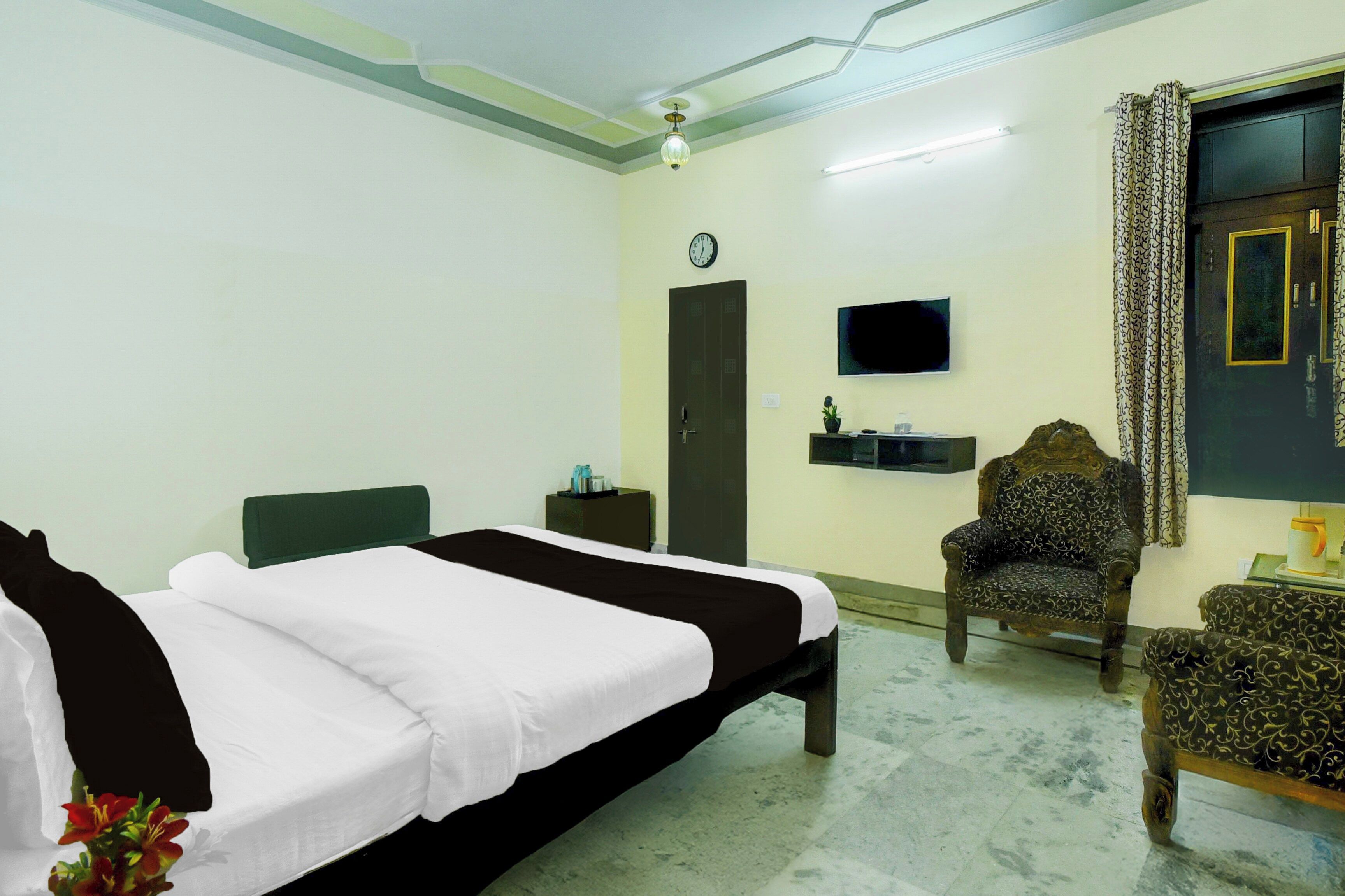 Una habitación de hotel con cama, una silla, televisor y puerta.