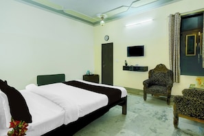 Una habitación de hotel con cama, una silla, televisor y puerta.