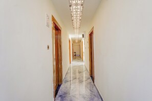 A hallway with wooden doors, a marble floor, and a decorative ceiling light fixture.