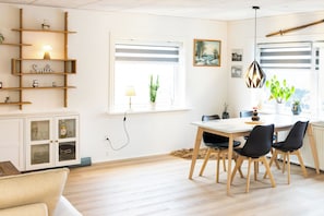 Ett modernt matområde med ett glasbord, trästolar och utsikt över omgivningen genom stora fönster.