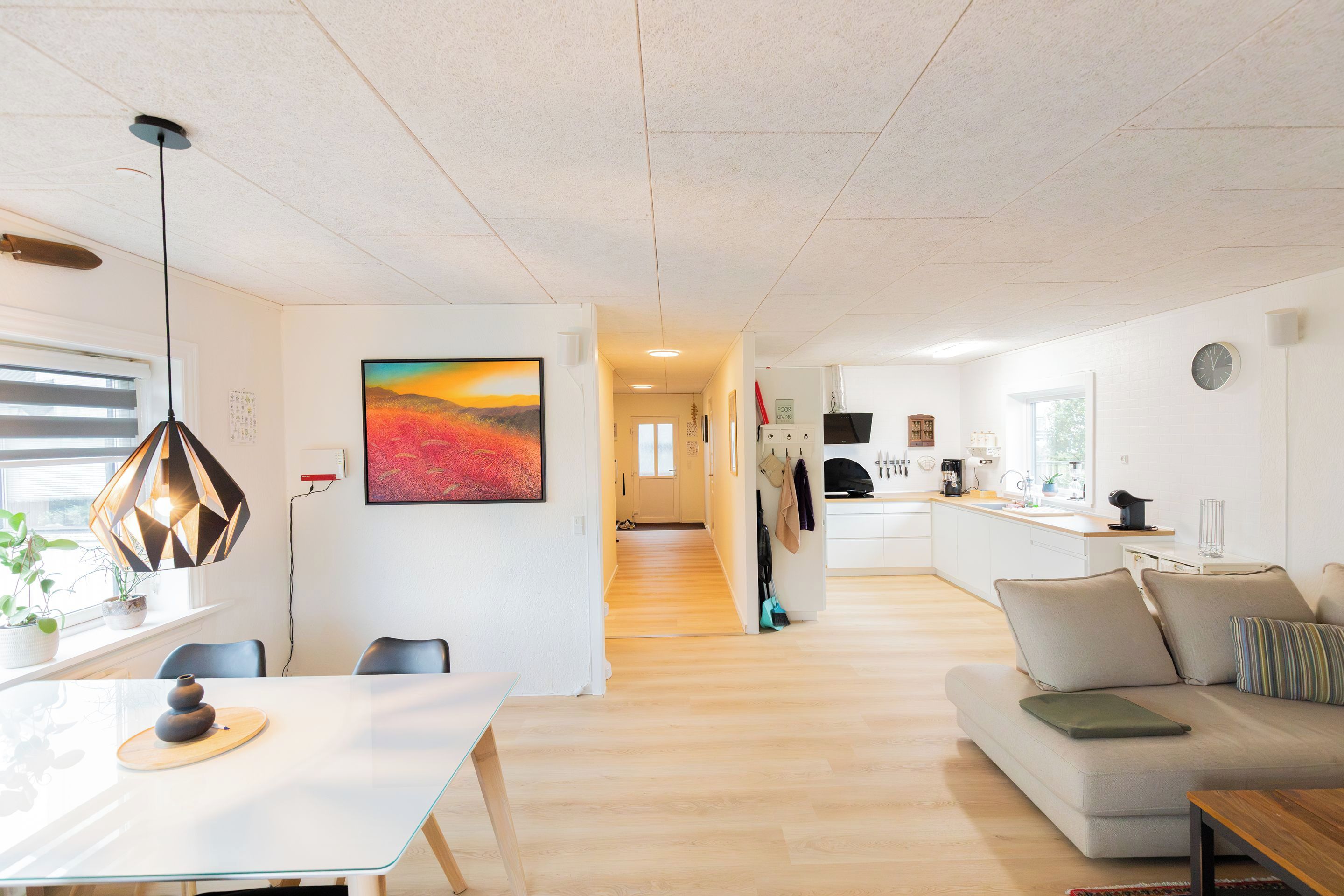 A modern living space with a dining area, kitchen, and a hallway leading to another room.
