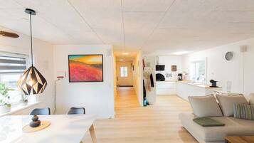A modern living space with a dining area, kitchen, and a hallway leading to another room.