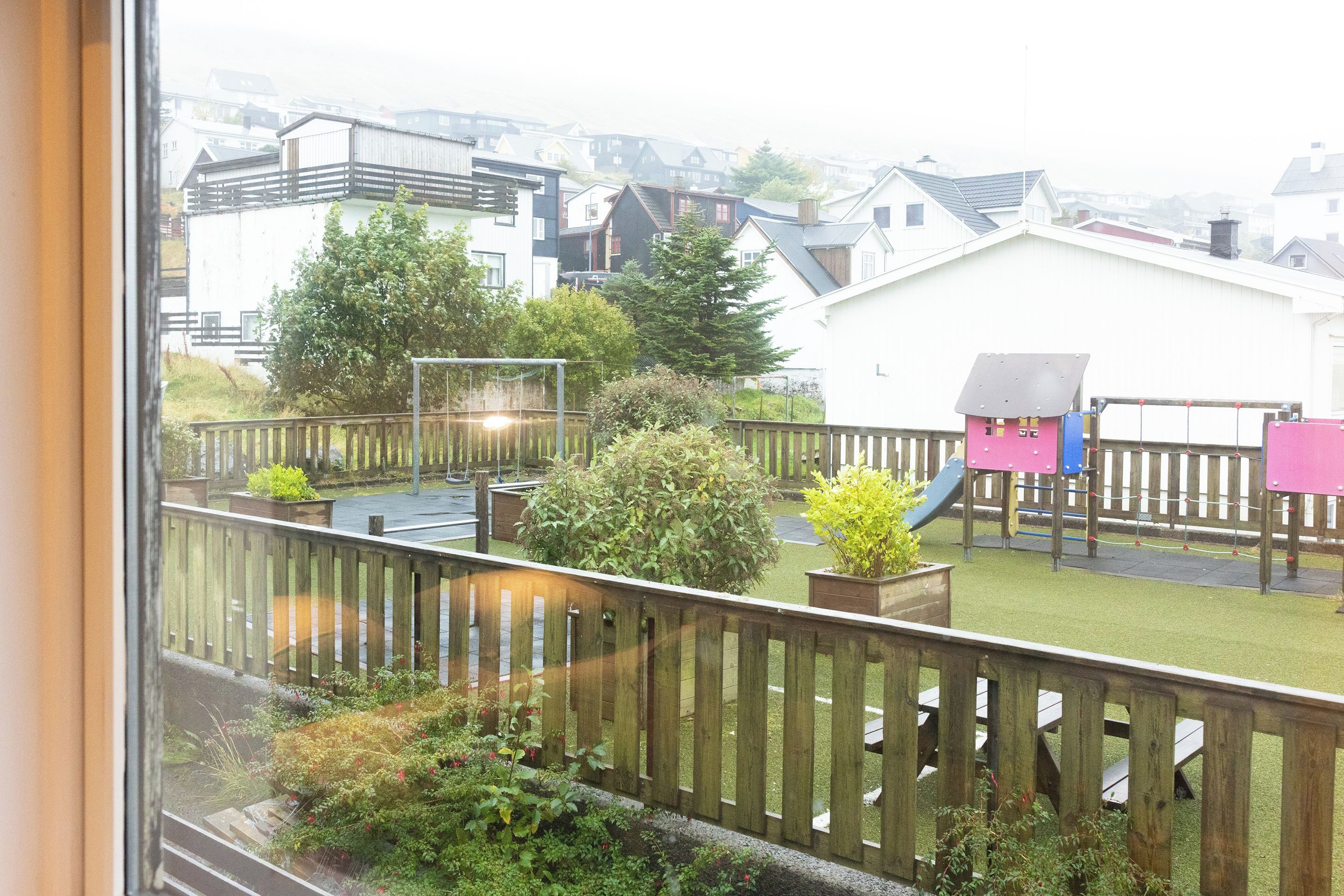 A residential area with a playground, a slide, and a wooden fence.