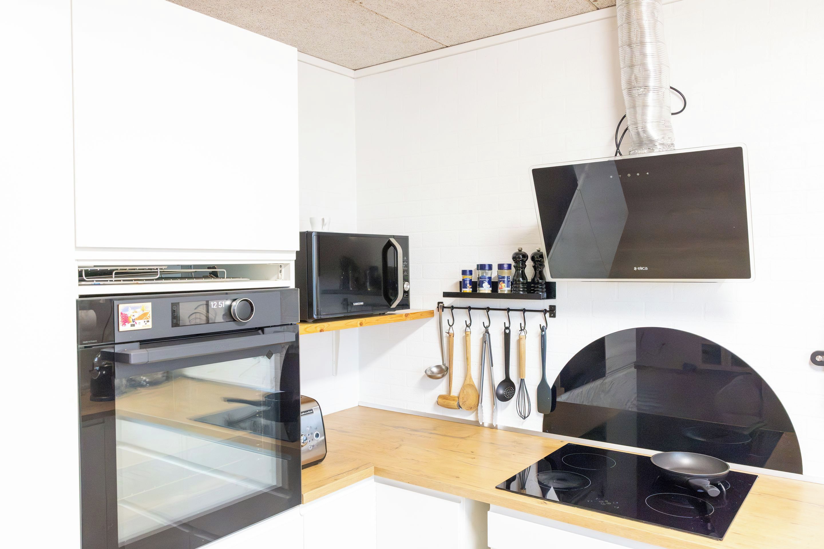 Una cocina compacta con horno integrado, microondas y cocina eléctrica.