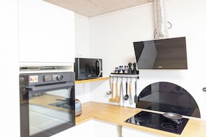 A compact kitchen with a built-in oven, microwave, and electric stove. - Kommunubrekka 8B (Klaksvík)