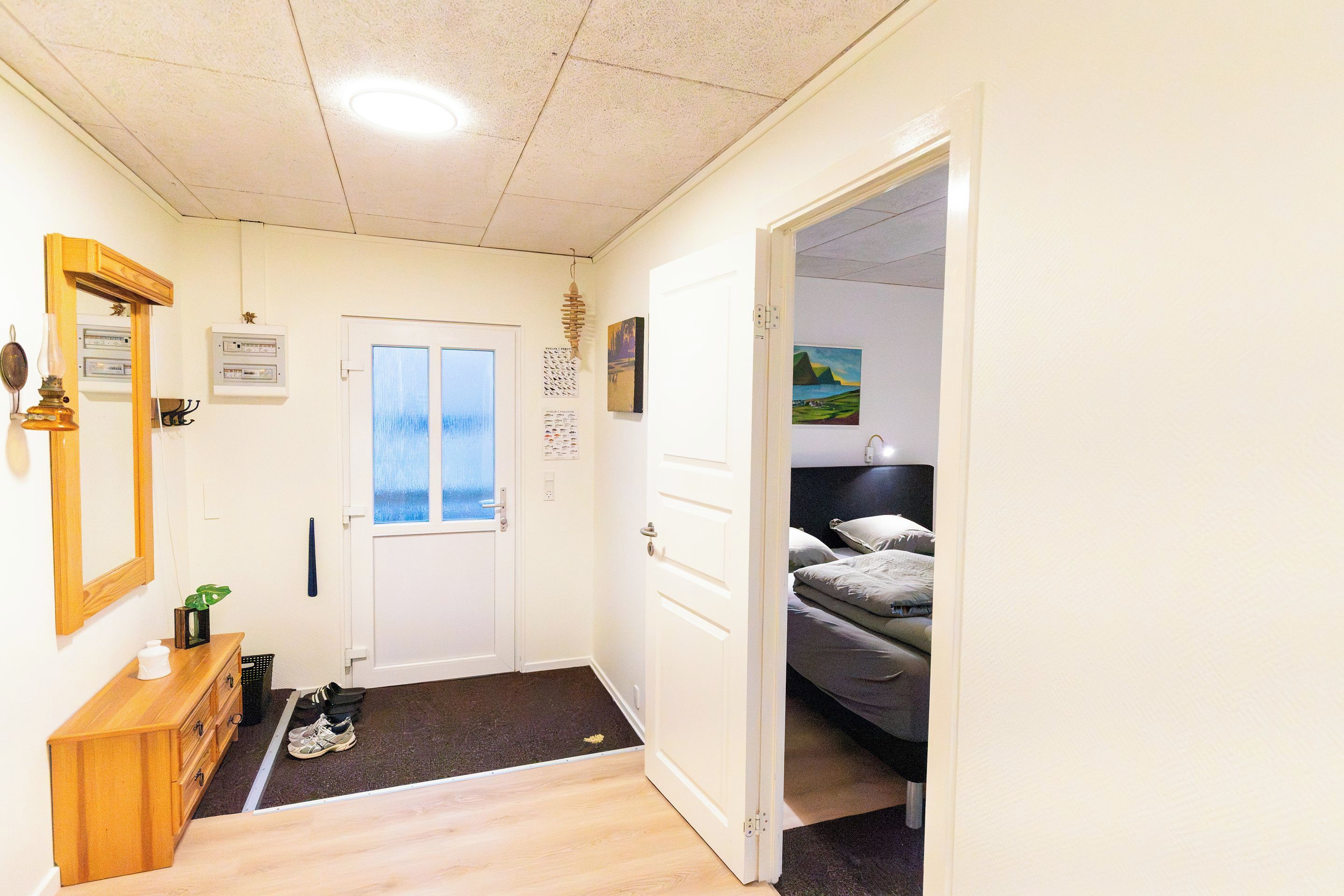Une chambre d’hôtel comprenant un lit, un bureau, un miroir et une porte donnant sur une autre pièce.