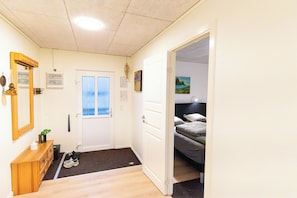 A hotel room with a bed, a desk, a mirror, and a door leading to another room. - Kommunubrekka 8B (Klaksvík)