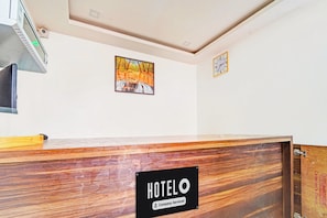 Un taulell de recepció d'hotel amb acabat de fusta, un rellotge i un quadre al mur.