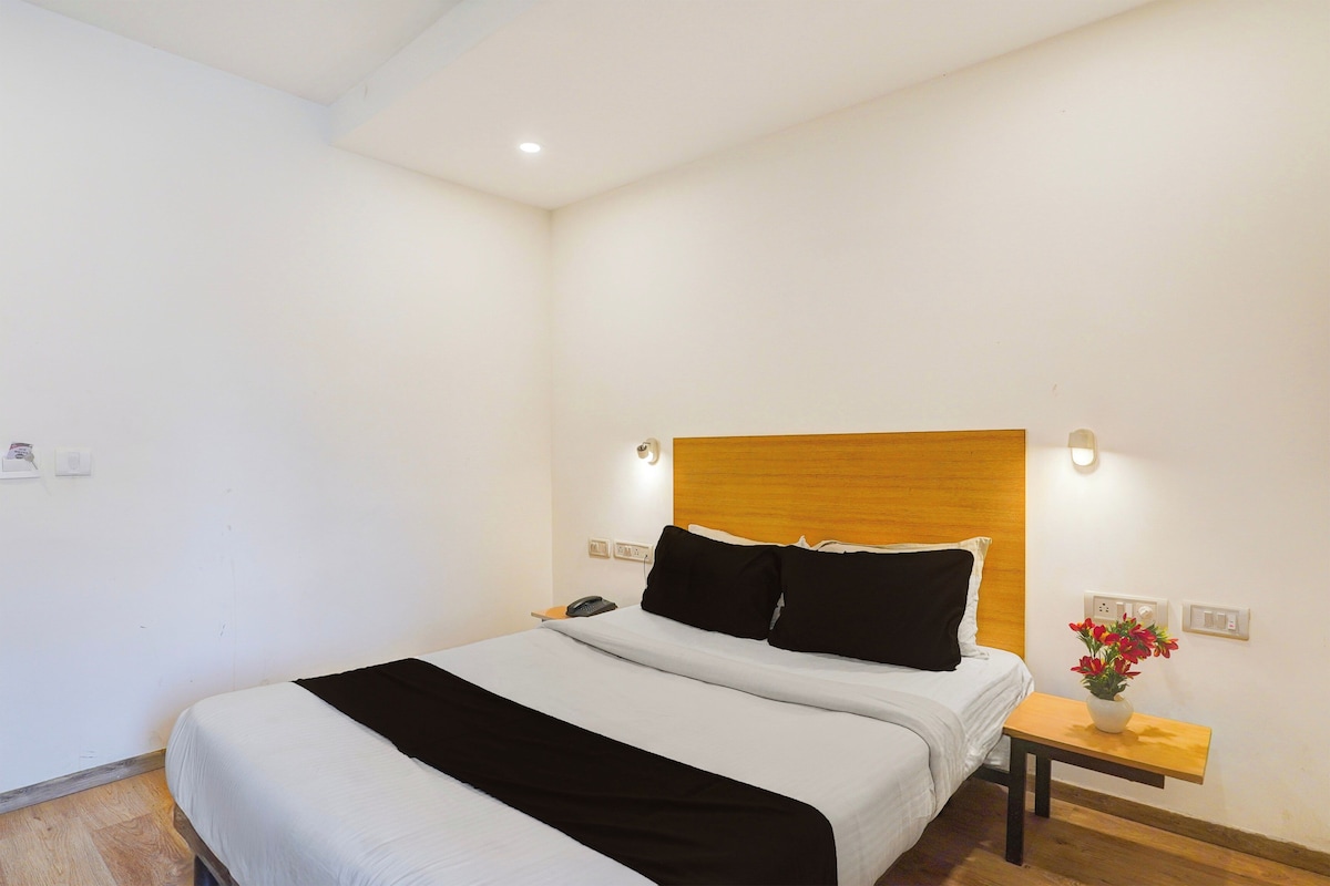 Una habitación de hotel con una cama, mesita de noche y un teléfono instalado en la pared.