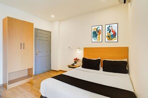 Un dormitorio con cama, armario y dos cuadros abstractos en la pared.