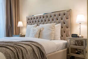 A neatly made bed with a tufted headboard, two bedside lamps, and a bedside table with a clock. - High-Floor 1BR, Walking Distance of the Metro and Short Drive from Burj Khalifa (Dubai)