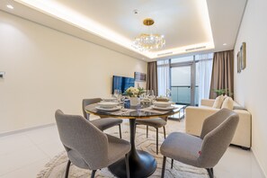 A modern dining area with a round table, four chairs, and a chandelier. - High-Floor 1BR, Walking Distance of the Metro and Short Drive from Burj Khalifa (Dubai)