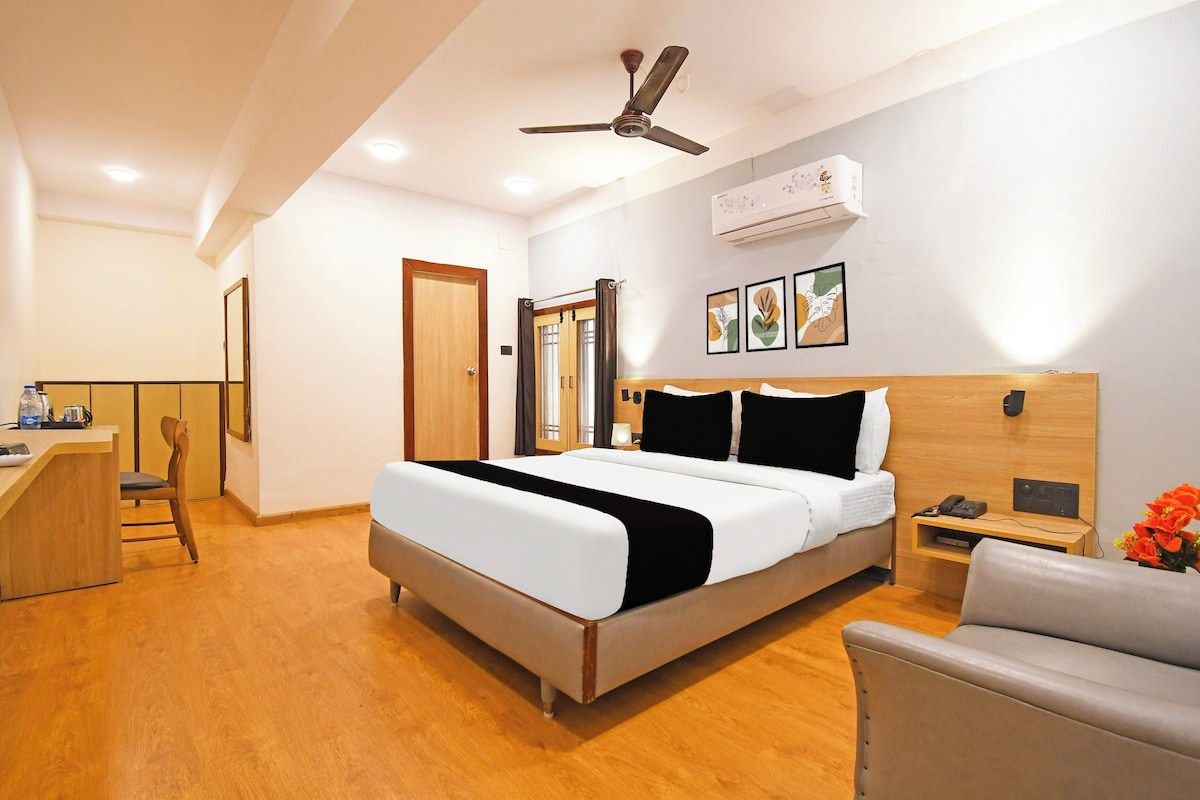 Habitación de hotel con cama, escritorio, silla, mesita de noche con teléfono y ventilador de techo.