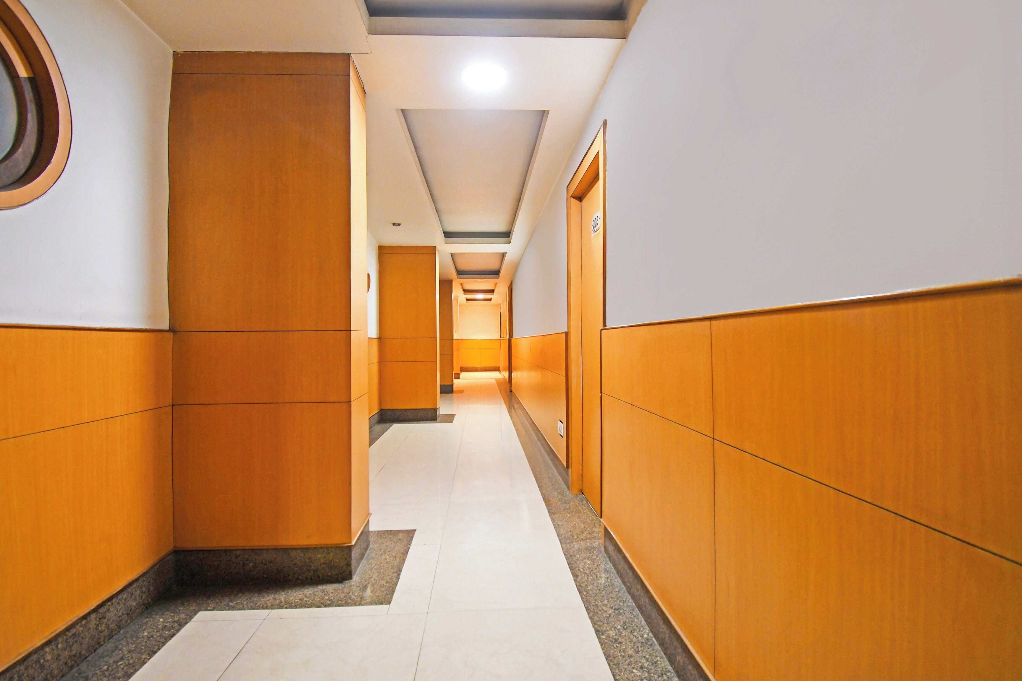 A corridor with wooden paneling, a tiled floor, and a ceiling with recessed lighting.