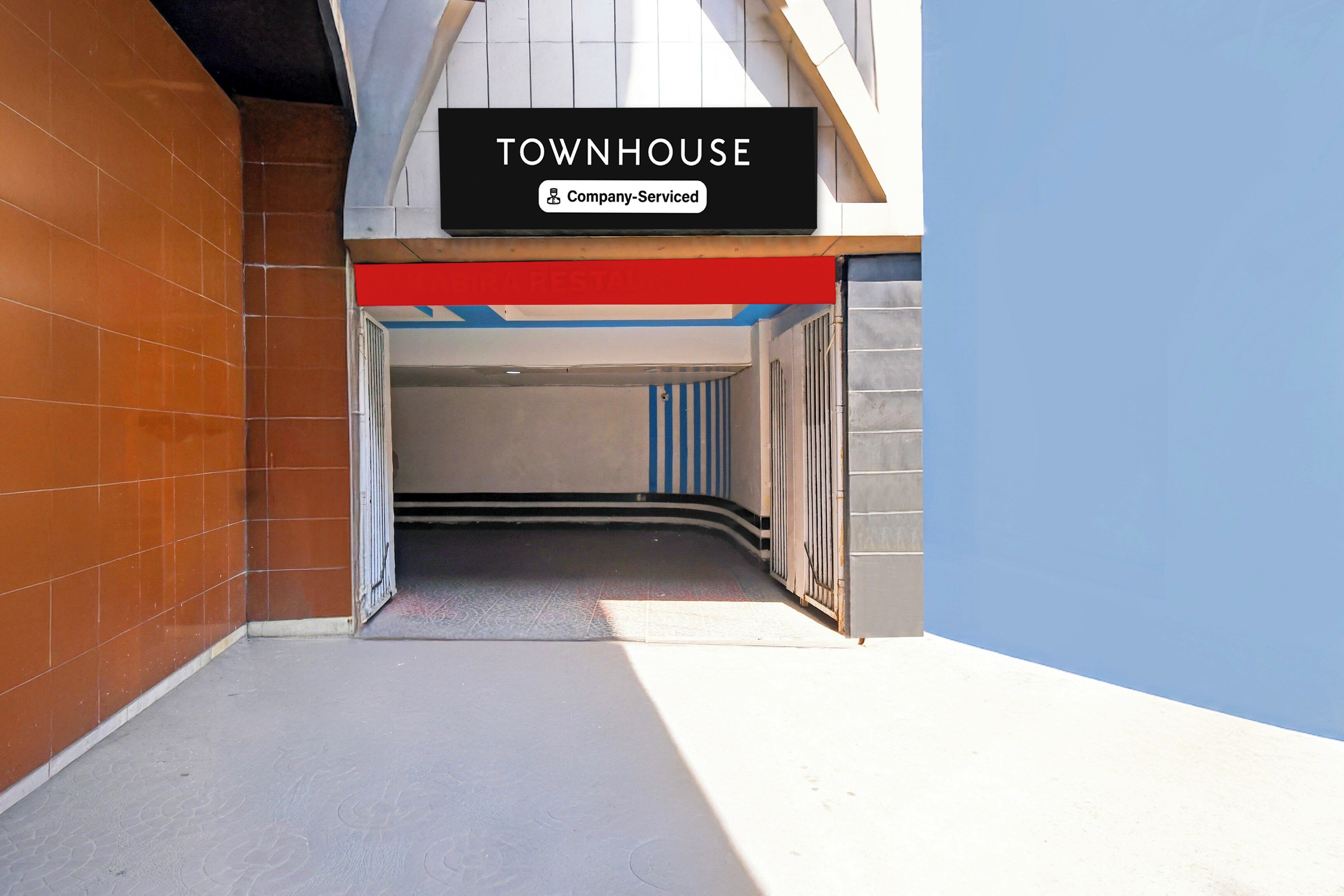 A corridor leading to a building labeled 'TOWNHOUSE' with a 'Company-Serviced' sign.