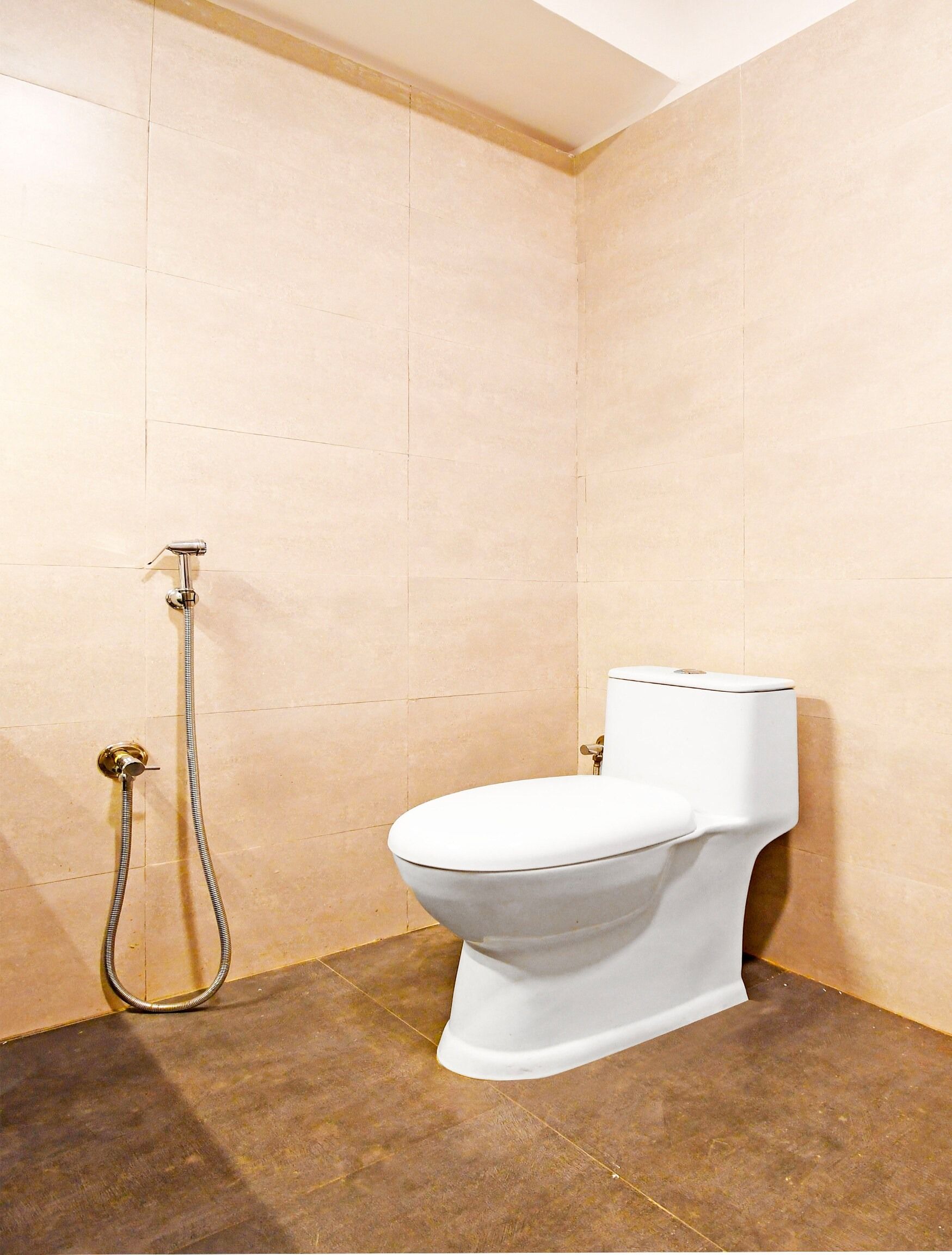 A bathroom with a toilet, a shower, and a tiled floor.