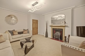 A living room with a sofa, coffee table, fireplace, and decorative items. - Yule House - North East Escapes (Alnwick)
