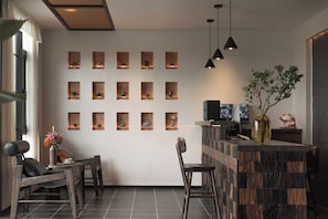 Un interior moderno con una zona de estar, una barra y una pared con múltiples lámparas cuadradas.