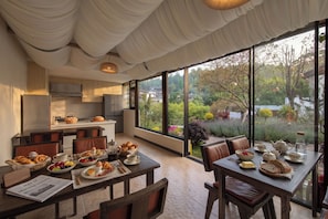 Cocina moderna con vistas a un jardín y un comedor con desayuno listo.
