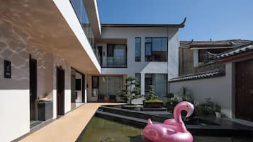 En moderne bygning med en pool, en lyserød flamingo-badering og traditionel arkitektur i baggrunden.