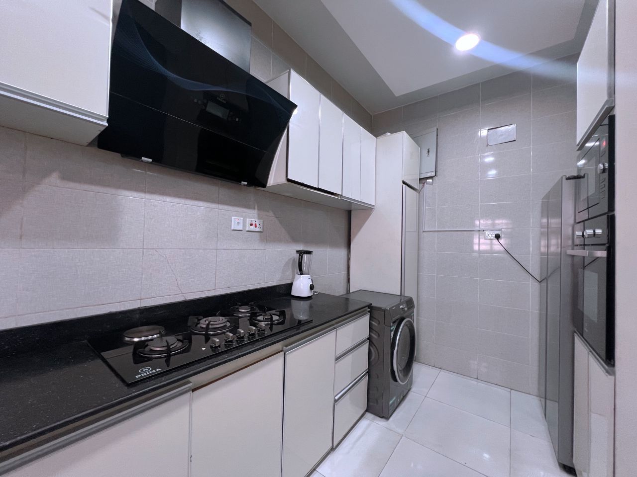 Una cocina moderna con estufa a gas, lavadora y horno empotrado.
