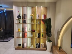 A modern bookshelf with various decorative items and books, a potted plant, and a dining area with a table and chairs.
