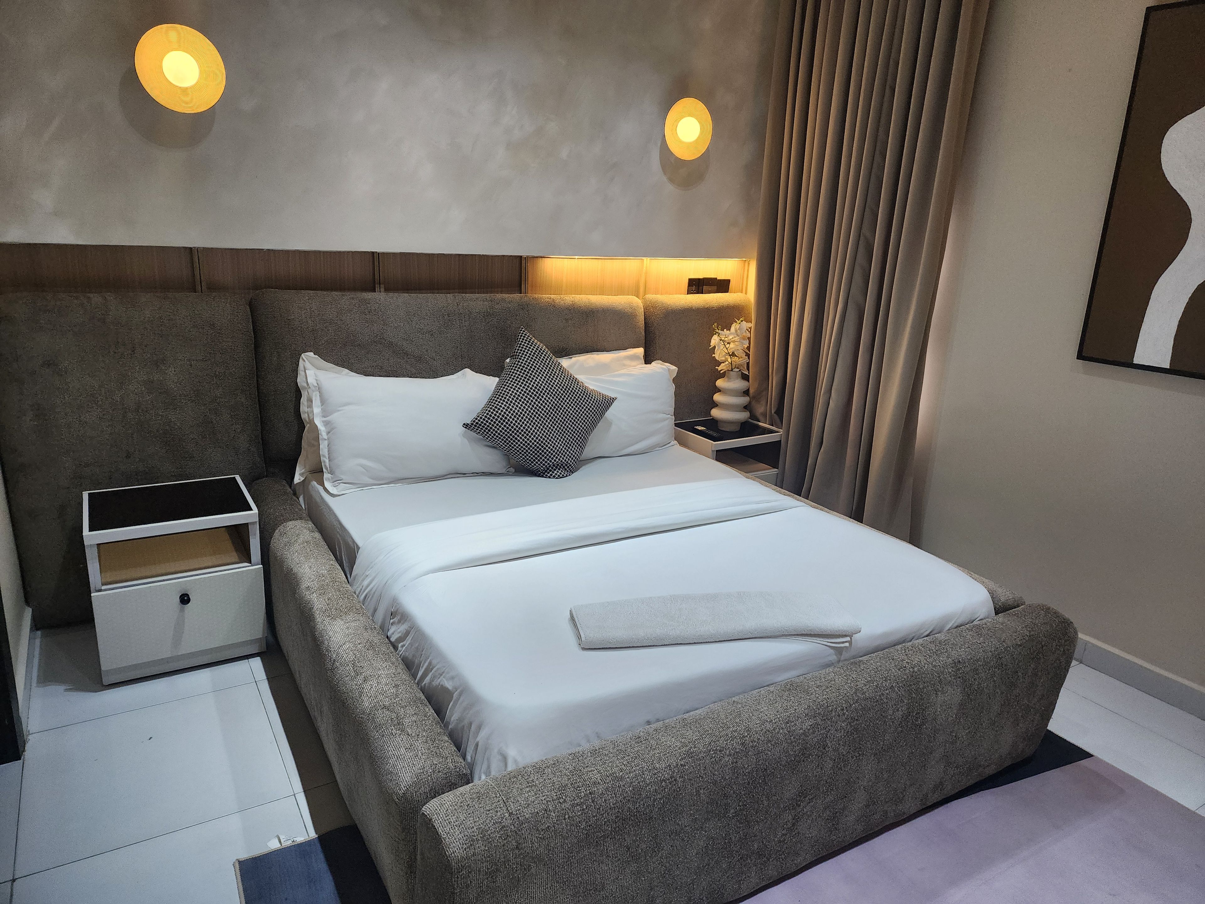 Une chambre à coucher moderne avec un grand lit, des tables de chevet et une petite table de nuit.