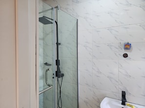 A glass-enclosed shower with a handheld showerhead and a handheld faucet. - L Rina Apartment Brown unit (Lekki)