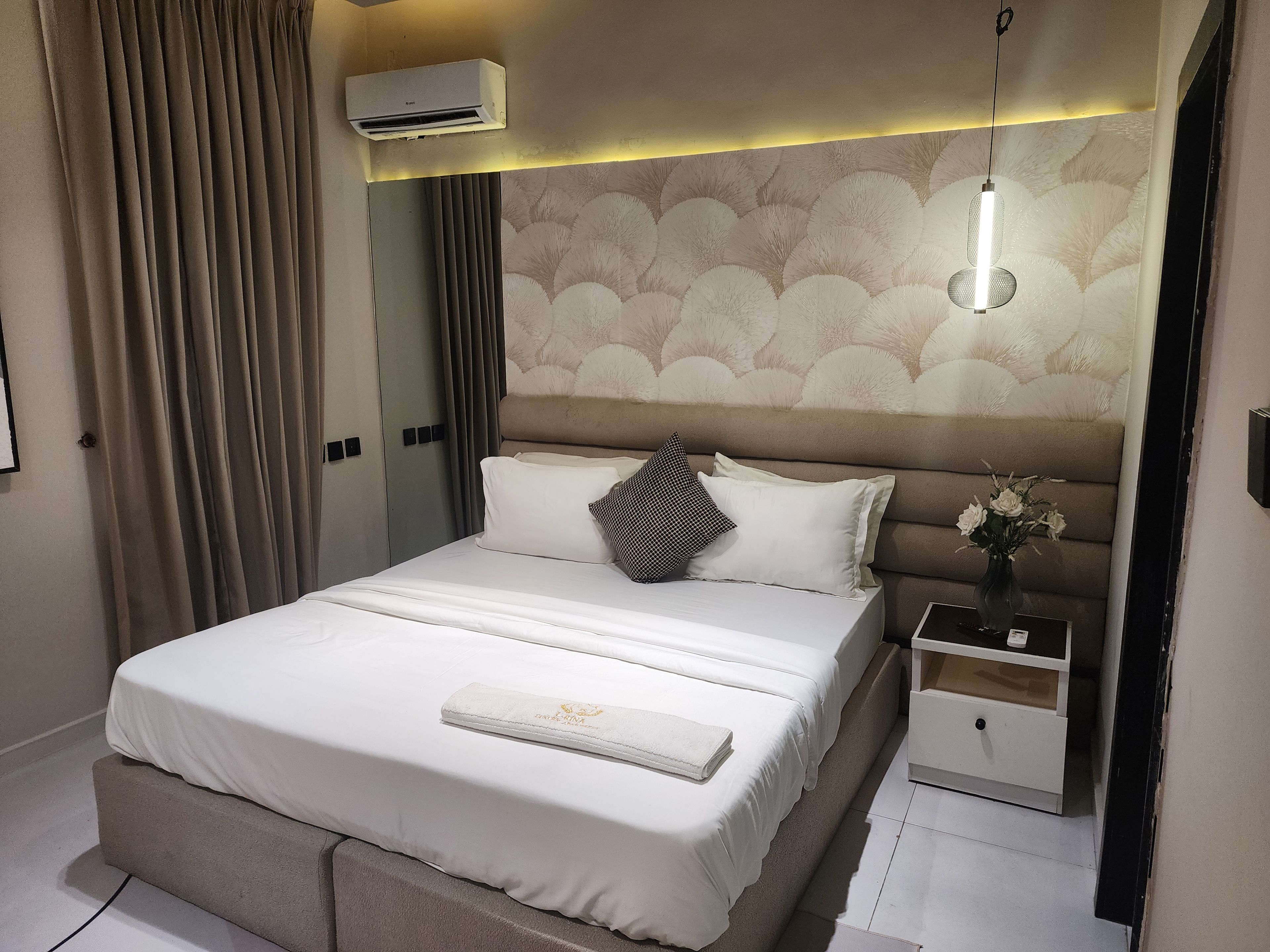 Ein Hotelzimmer mit einem Bett, einem Nachttisch und einer Klimaanlage.