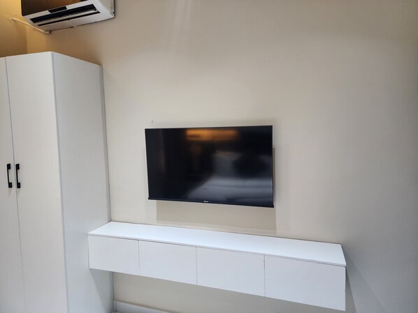 A white wall with a mounted flat-screen TV and a white cabinet below it.