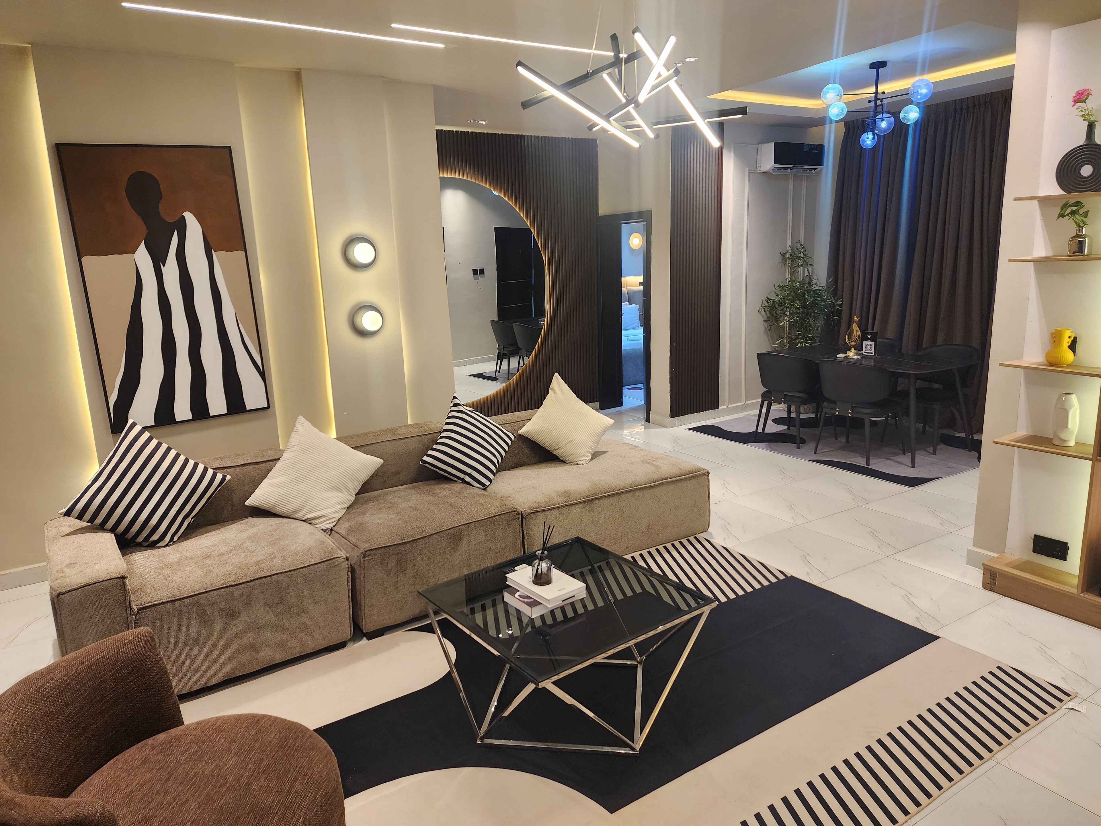 Un salon moderne avec un canapé d’angle, une table basse en verre et un coin repas comprenant une table et des chaises noires.