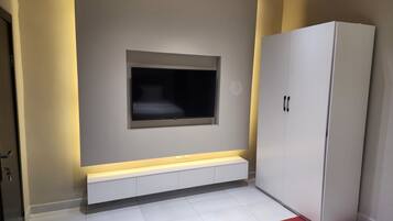 Une pièce dotée d’un téléviseur à écran plat fixé au mur, d’une armoire blanche et d’un tapis rouge qui apporte une touche de couleur au sol.