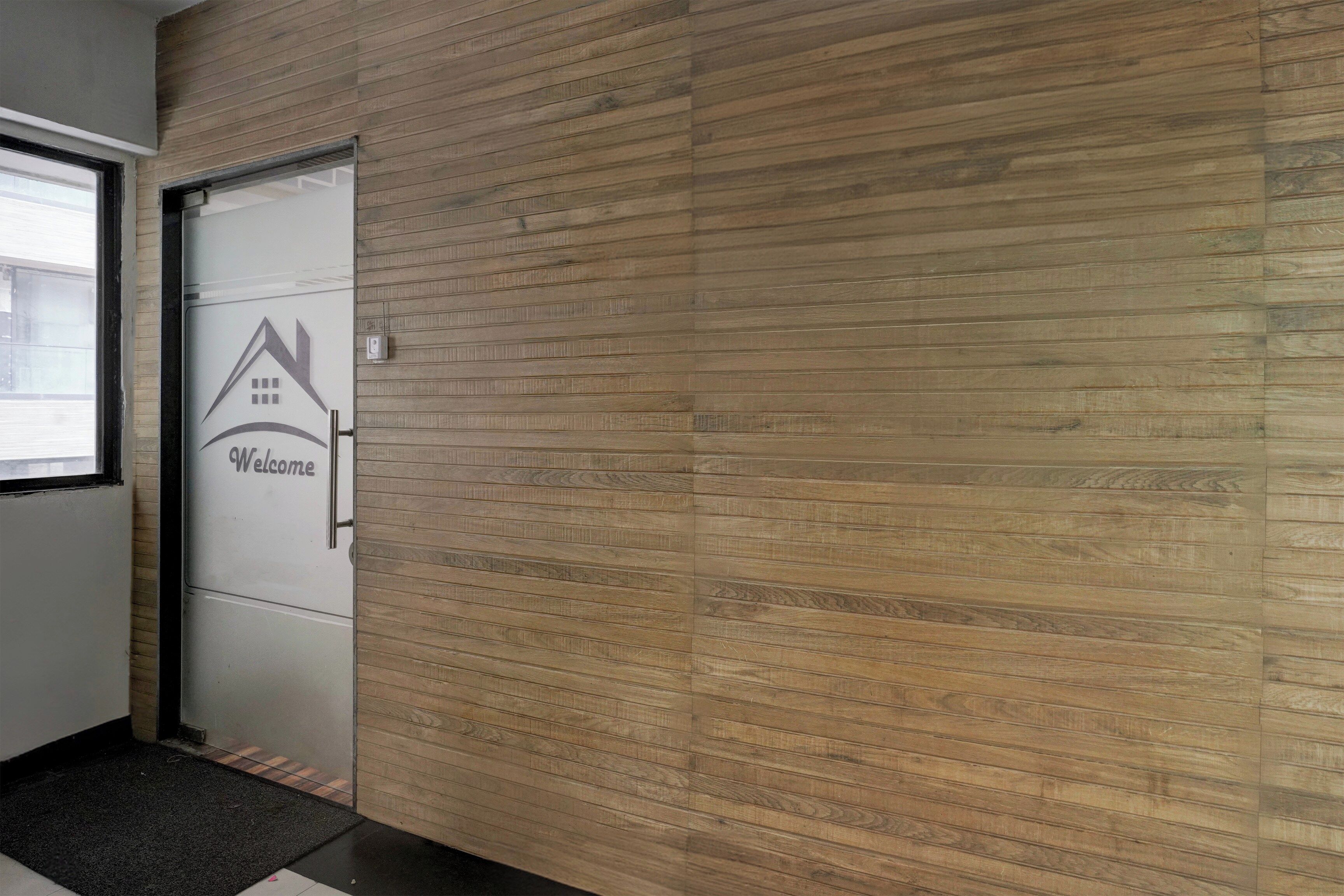A hallway with a wooden wall and a door with a welcome sign.