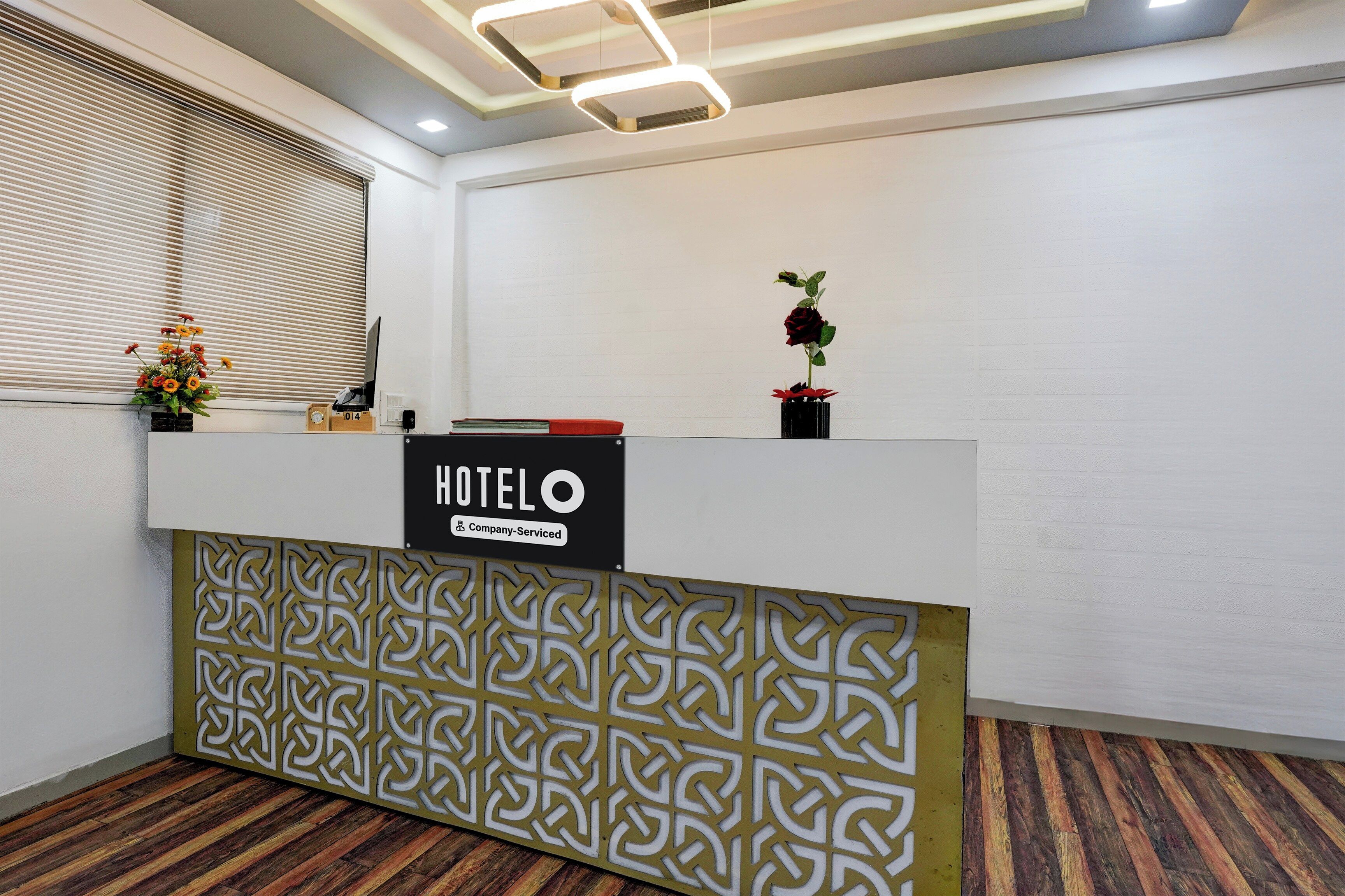 Een hotel receptiebalie met een bord met bedrijfsreclame, een bloevas en een kamerplant.