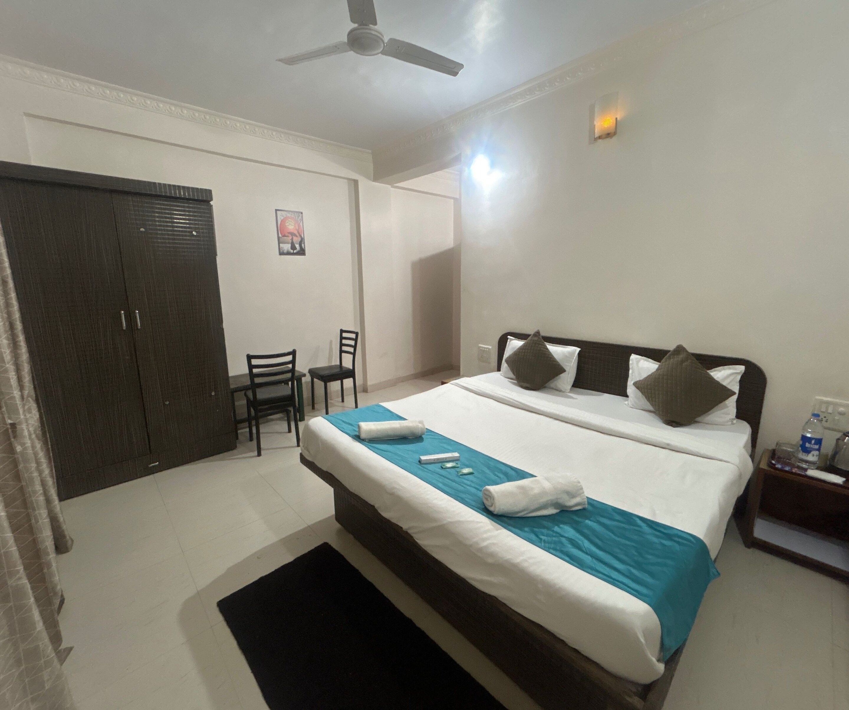 A hotel room with a bed, a desk, a chair, and a wardrobe.