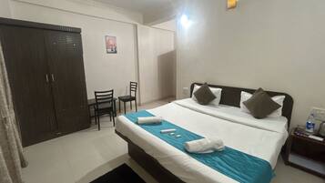 A hotel room with a bed, a desk, a chair, and a wardrobe.