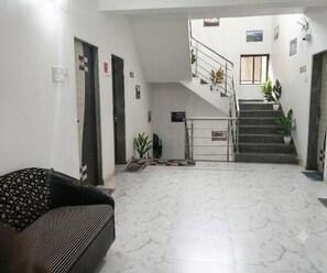 A lobby with a staircase, a sofa, and a door. - Classic Oraa Stay (Mahabaleshwar)