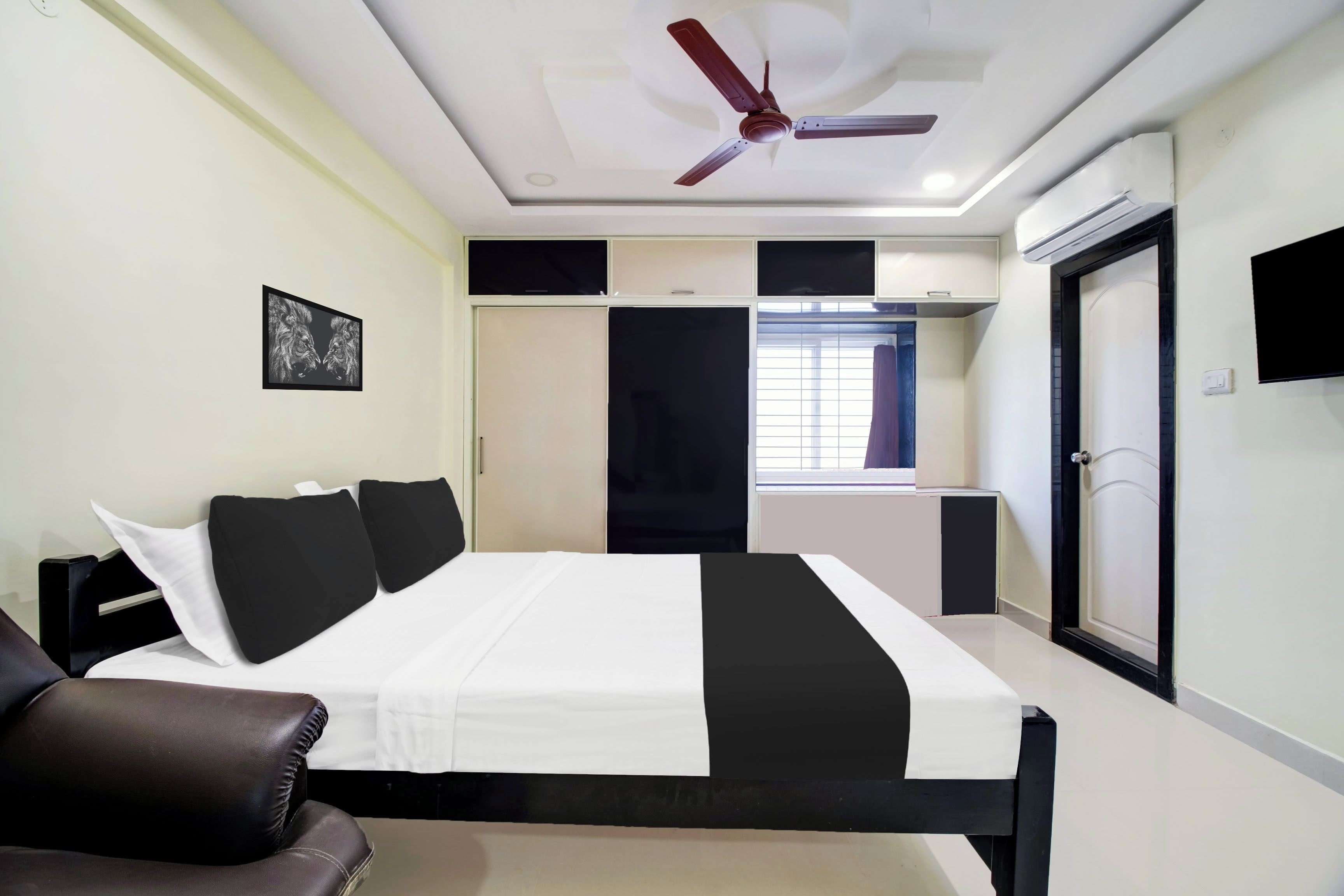 Une chambre à coucher avec un lit, un ventilateur de plafond, une armoire et un téléviseur.