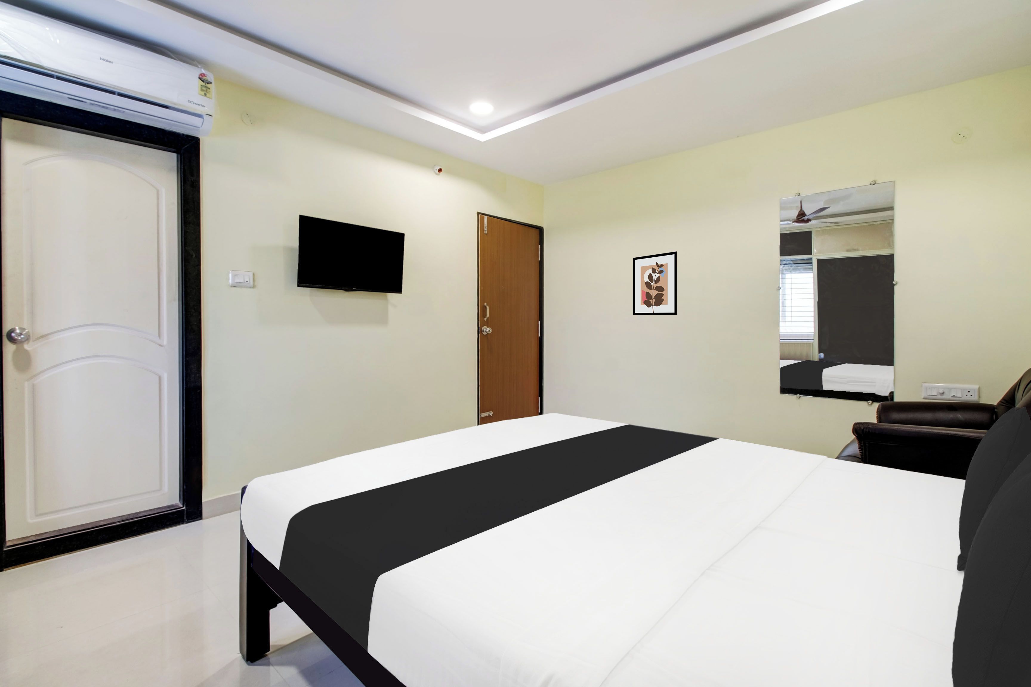 Una habitación de hotel con una cama, televisión, puerta y espejo.
